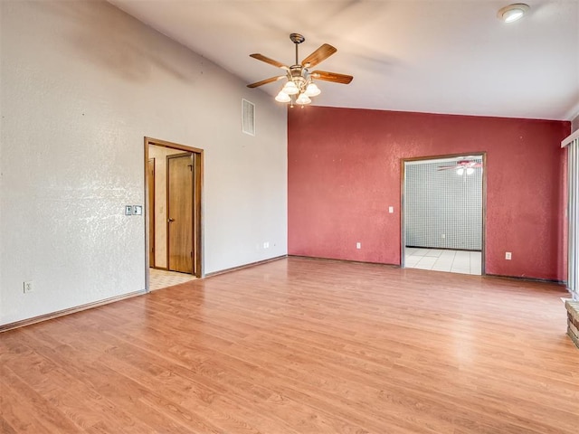 empty room featuring vaulted ceiling, light hardwood / wood-style floors, and ceiling fan