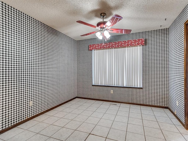 tiled empty room featuring ceiling fan and a textured ceiling