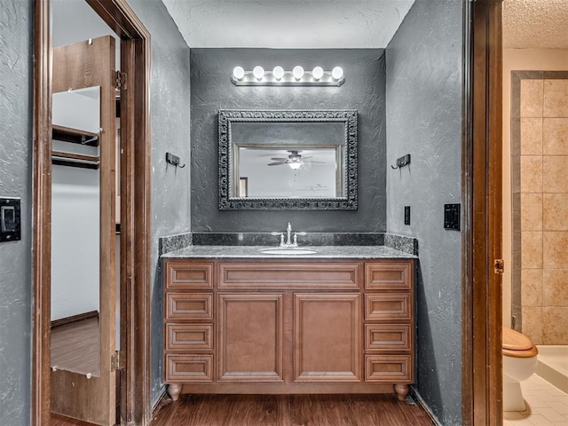 bathroom with hardwood / wood-style flooring, vanity, a textured ceiling, and toilet