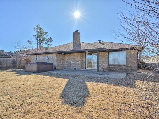 back of house featuring a lawn, a hot tub, and a patio