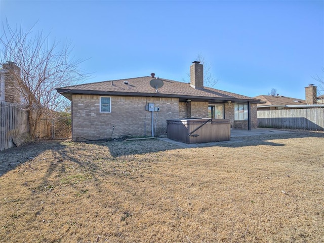 back of house featuring a hot tub, a yard, and a patio area