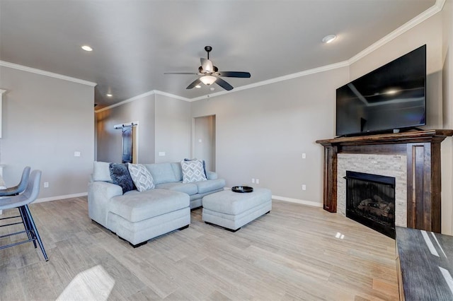 living room featuring crown molding, a stone fireplace, light hardwood / wood-style floors, and ceiling fan