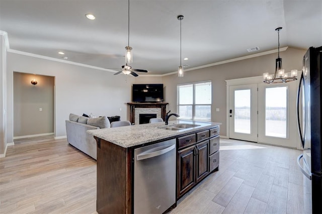 kitchen featuring black refrigerator, sink, stainless steel dishwasher, dark brown cabinetry, and a center island with sink