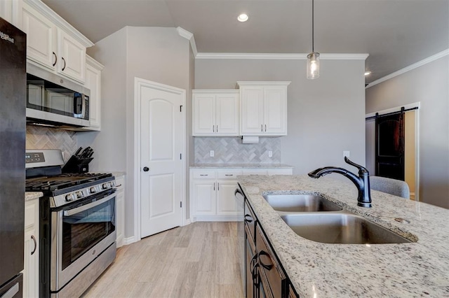 kitchen featuring stainless steel appliances, a barn door, sink, and white cabinets