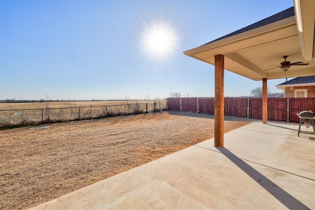 view of yard featuring a rural view, ceiling fan, and a patio area