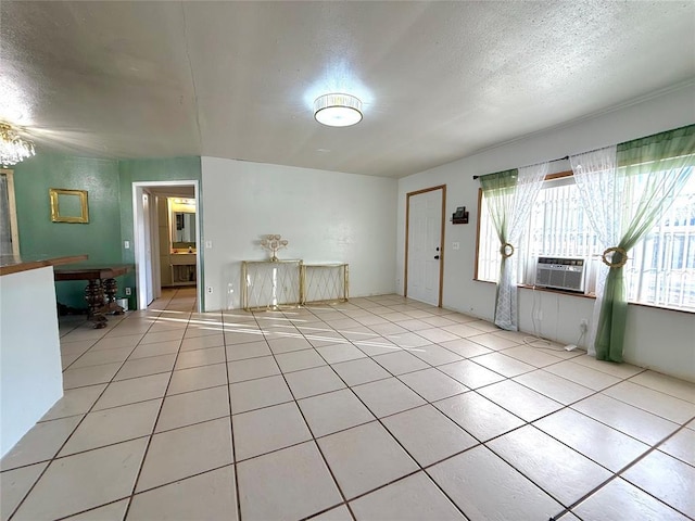 foyer featuring cooling unit, light tile patterned floors, and a textured ceiling