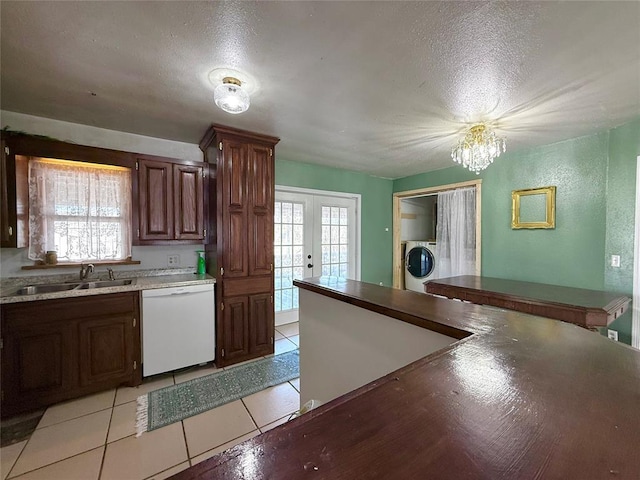 kitchen with a textured ceiling, washer / clothes dryer, sink, light tile patterned flooring, and white dishwasher