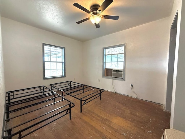 bedroom featuring hardwood / wood-style floors, multiple windows, cooling unit, and ceiling fan