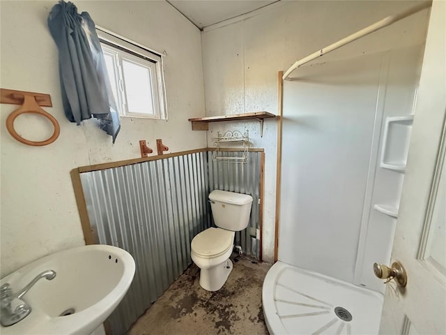 bathroom with concrete floors, a shower, and toilet