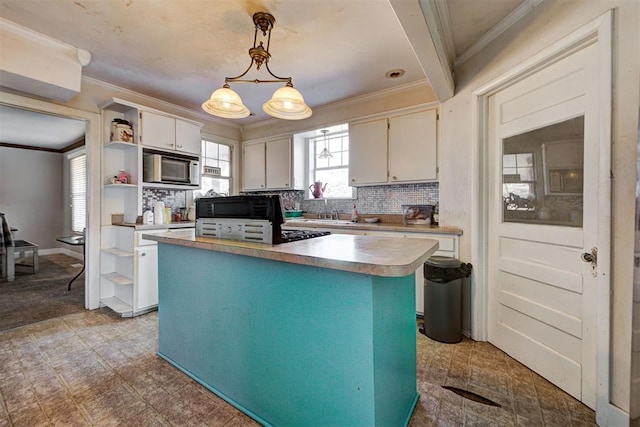 kitchen with crown molding, white cabinetry, tasteful backsplash, built in microwave, and decorative light fixtures