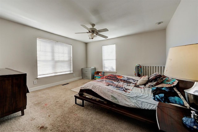 bedroom featuring ceiling fan, light colored carpet, and multiple windows