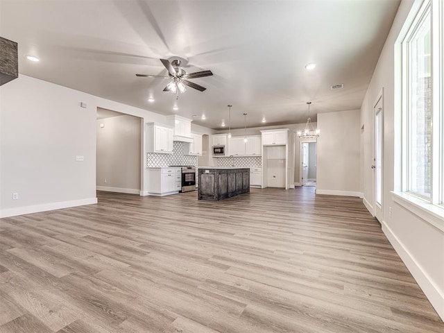 unfurnished living room with ceiling fan with notable chandelier and light hardwood / wood-style flooring