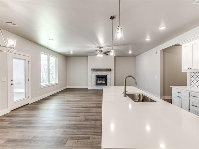 kitchen featuring white cabinetry, sink, pendant lighting, and a fireplace