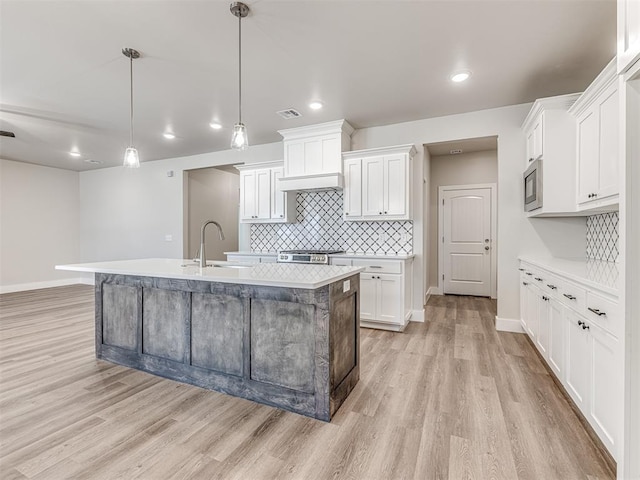 kitchen featuring pendant lighting, built in microwave, sink, and white cabinets