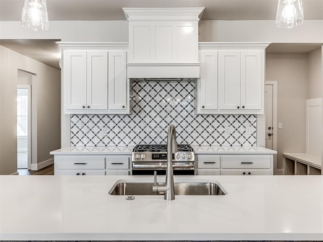 kitchen featuring hanging light fixtures, white cabinetry, and stainless steel stove