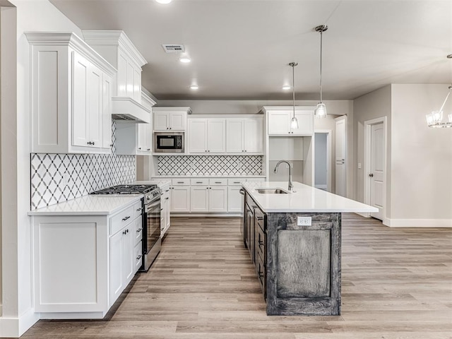 kitchen featuring black microwave, pendant lighting, gas stove, and white cabinets