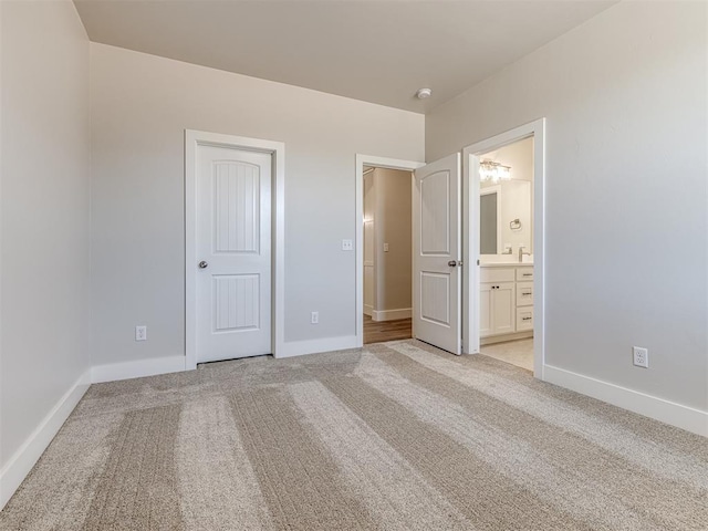 unfurnished bedroom featuring light colored carpet and ensuite bathroom