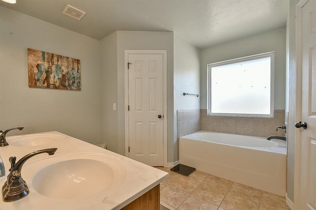 bathroom featuring vanity, tile patterned floors, and a tub