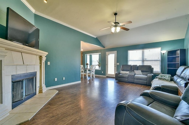 living room with lofted ceiling, hardwood / wood-style flooring, crown molding, a tile fireplace, and ceiling fan