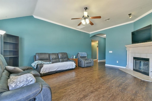 living room featuring vaulted ceiling, dark hardwood / wood-style floors, a fireplace, ornamental molding, and ceiling fan