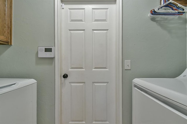 clothes washing area with cabinets and washing machine and clothes dryer