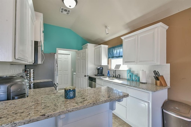 kitchen featuring lofted ceiling, appliances with stainless steel finishes, white cabinetry, tasteful backsplash, and kitchen peninsula