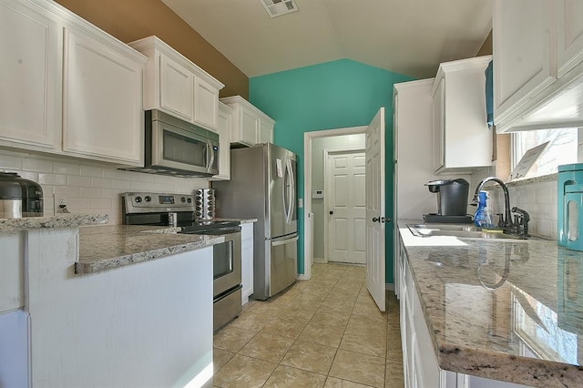 kitchen featuring vaulted ceiling, white cabinetry, sink, backsplash, and stainless steel appliances