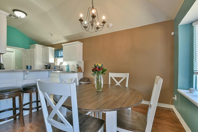 dining room with an inviting chandelier, dark hardwood / wood-style flooring, and vaulted ceiling