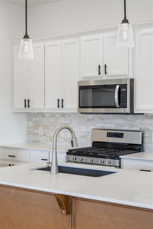 kitchen featuring pendant lighting, white cabinetry, and stainless steel appliances