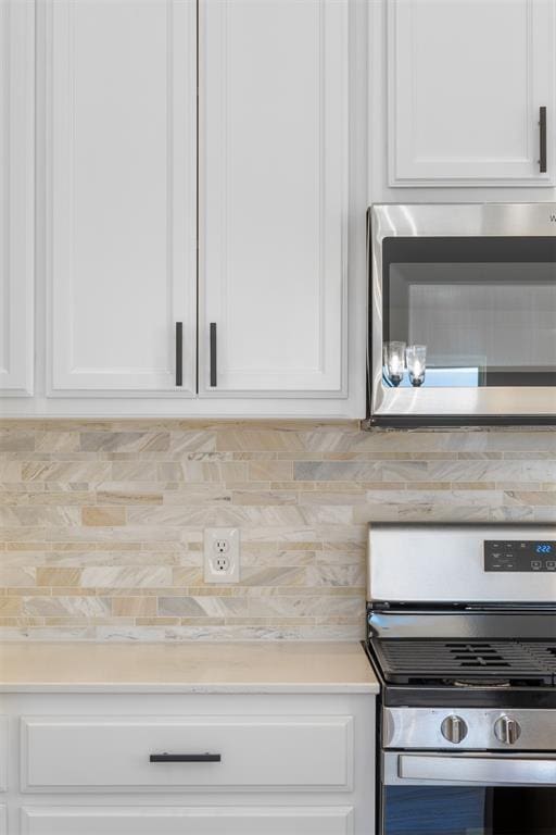 kitchen featuring stainless steel appliances, white cabinets, and backsplash