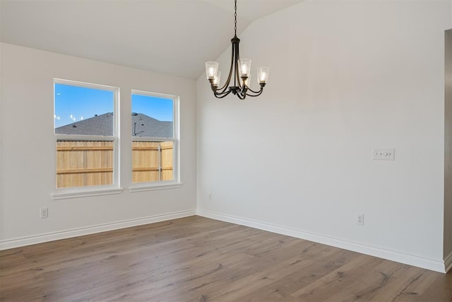 unfurnished dining area with lofted ceiling, hardwood / wood-style floors, and a notable chandelier