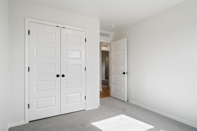 unfurnished bedroom featuring light colored carpet and a closet