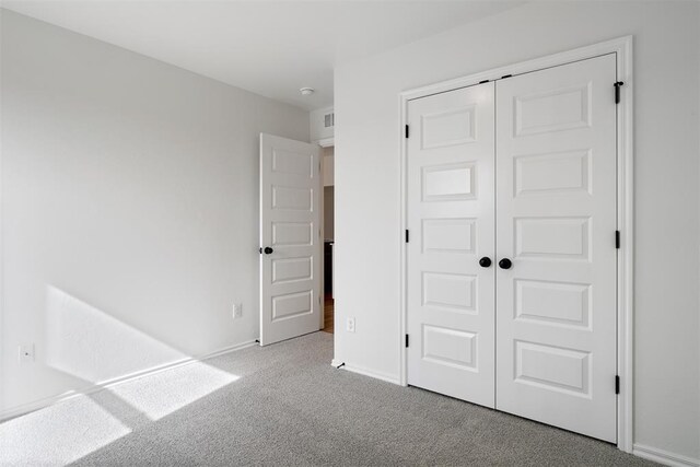 unfurnished bedroom featuring light colored carpet and a closet