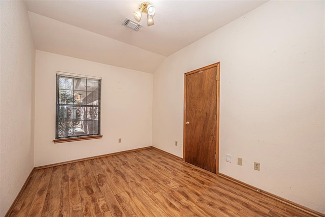 spare room featuring lofted ceiling and hardwood / wood-style floors