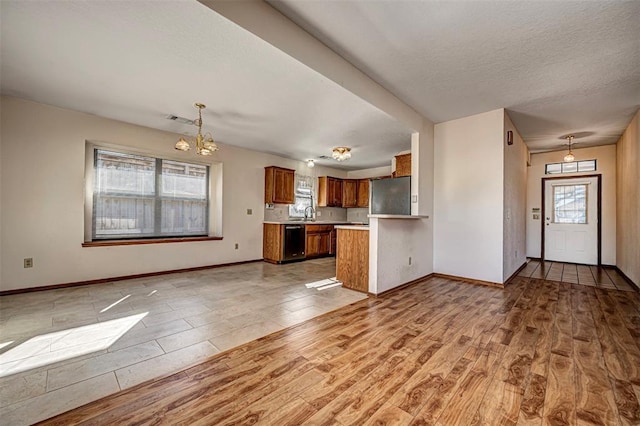 kitchen featuring black dishwasher, refrigerator, kitchen peninsula, and hanging light fixtures