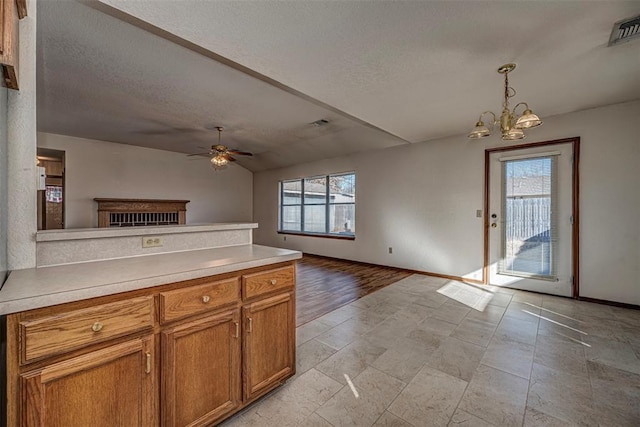 kitchen featuring ceiling fan with notable chandelier, plenty of natural light, pendant lighting, and a textured ceiling