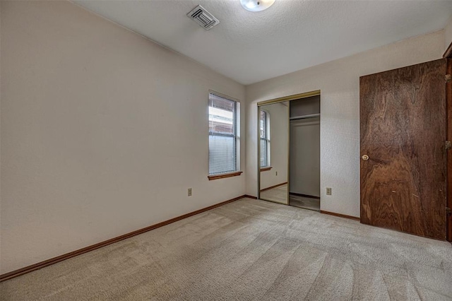 unfurnished bedroom with light carpet and a closet