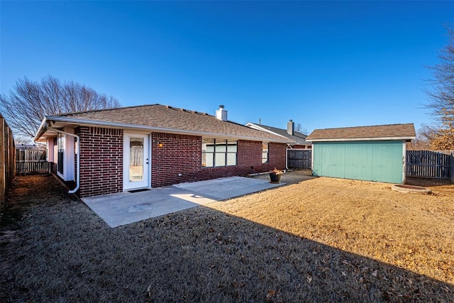 rear view of property featuring a patio and a storage unit