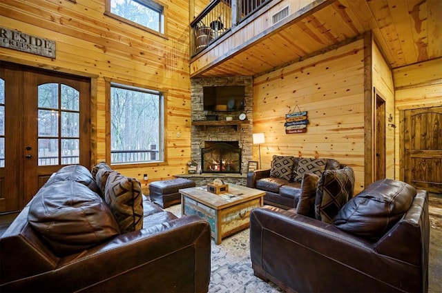 living room featuring plenty of natural light, a stone fireplace, and wood walls