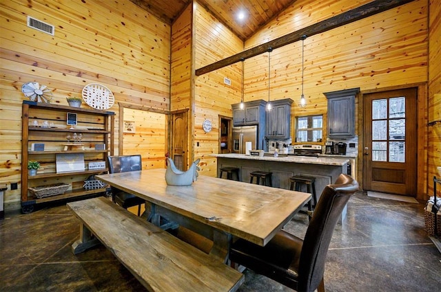 dining area with wood ceiling, a towering ceiling, and wooden walls