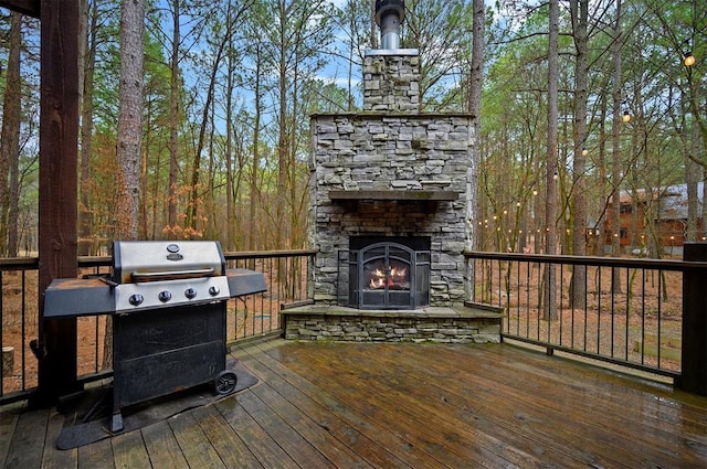 wooden terrace featuring grilling area and an outdoor stone fireplace