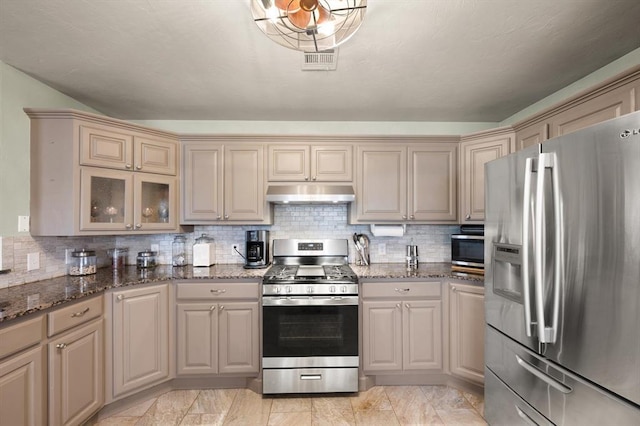 kitchen featuring stainless steel appliances, decorative backsplash, and dark stone countertops