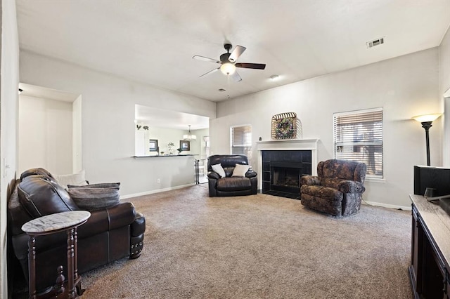 living room with a tiled fireplace, carpet, and ceiling fan