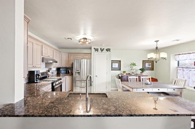 kitchen featuring sink, a chandelier, kitchen peninsula, pendant lighting, and stainless steel appliances