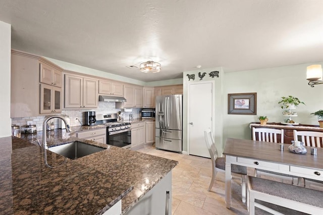 kitchen with appliances with stainless steel finishes, sink, dark stone countertops, and kitchen peninsula