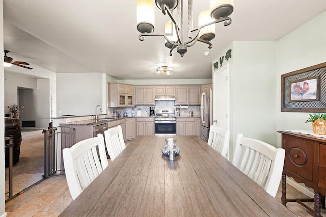 dining space featuring sink and ceiling fan with notable chandelier