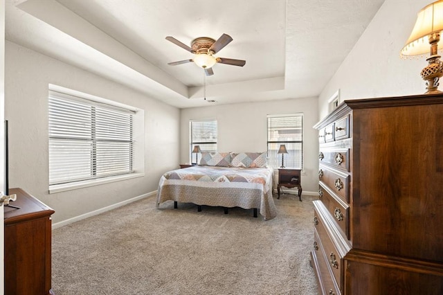 bedroom featuring a raised ceiling, carpet floors, and ceiling fan