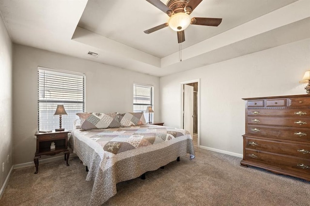 carpeted bedroom with a raised ceiling and ceiling fan