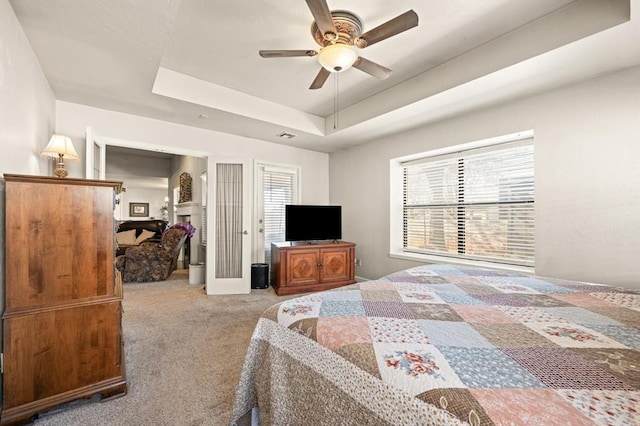 bedroom with french doors, light colored carpet, ceiling fan, and a tray ceiling