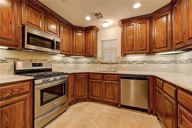 kitchen featuring light stone countertops, sink, stainless steel appliances, and tasteful backsplash